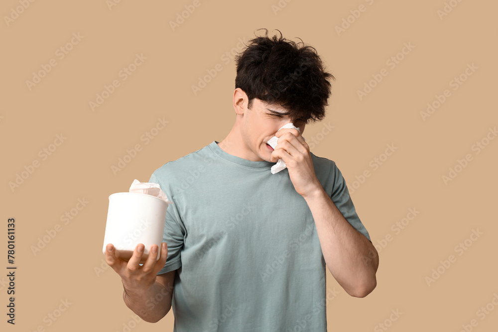 Young man with runny nose on beige background. Allergy concept Young man with runny nose on beige background. Allergy concept