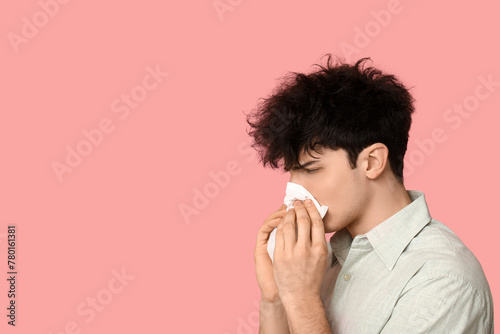 Young man with runny nose on pink background. Allergy concept