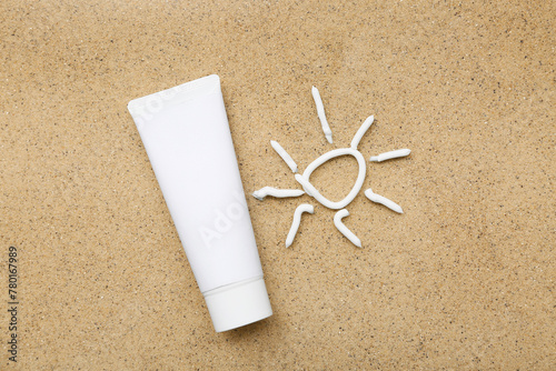 Sun made of cream with tube of sunscreen on sand background