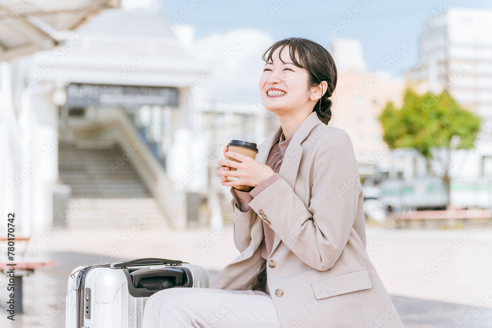 Φωτογραφία 出張・旅行でバス停・タクシー乗り場・待合所でコーヒー・紅茶を飲む女性（待ち合わせ）