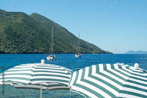 View of boats in the sea with beach umbrellas in the foreground