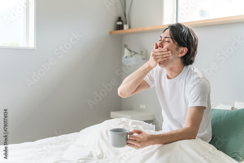 朝起床してベッドであくびする男性（睡眠・覚醒・眠り）
 photo