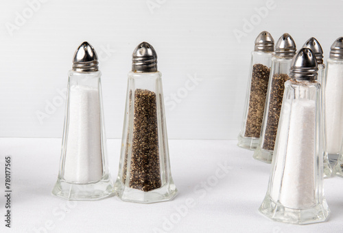 imple American restaurant or diner style salt and pepper shakers on a white table arranged as if they were people on a dance floor