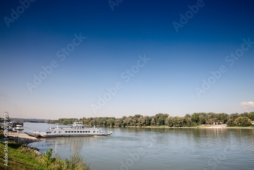 Panorama of the danube river in Mohacs, Hungary, with a ferro boat, Mohacsi komp, ready to cross the Danube from Mohacs to Ujmohacs, carrying cars and goods. © Jerome