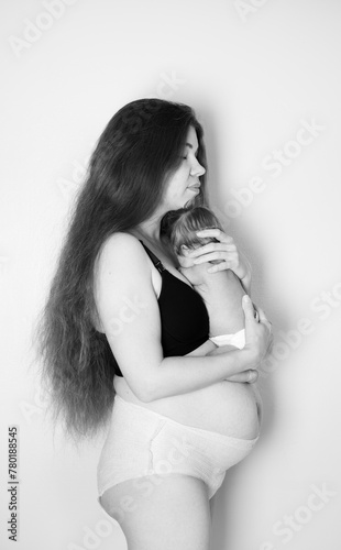 Postpartum woman with her newborn baby. Postpartum body. Body positivity. Real, authentic picture of a woman after giving birth to a baby. Woman holding her newborn daughter. Black and white photo