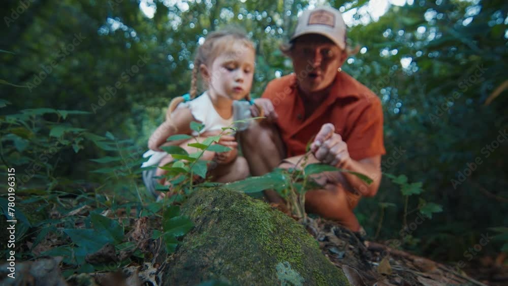 Family science. Adult man with kid sit in the tropical forest and watch ants running on the ground. Father shows his daughter wonders of the nature Family science. Adult man with kid sit in the tropical forest and watch ants running on the ground. Father shows his daughter wonders of the nature