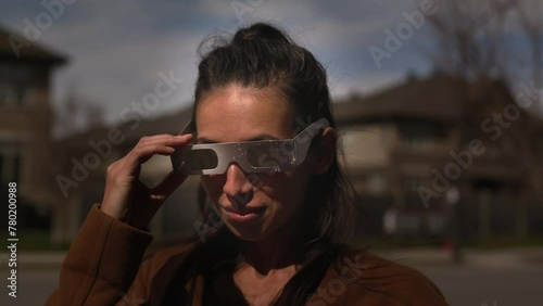 Woman finsihes watchin solar eclipse in front yard - takes off glasses photo