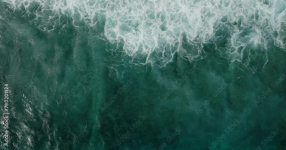 Aerial view of a wave crashing on winter beach covered in snow Aerial view of a wave crashing on winter beach covered in snow