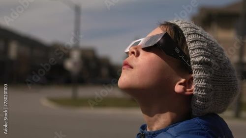 Young boy stares at sun with solar glasses on for eclipse - side profile