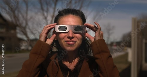 Woman puts on solar glasses and looks up towards solar eclipse - head on shot