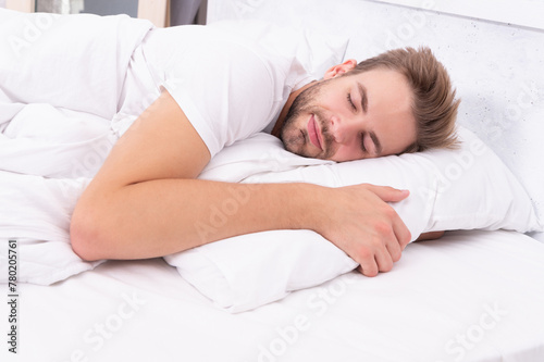 Lying with closed eyes. Deep male sleep. Man sleeping at night. Sleepy man lying on bed sleeping at white bedroom. Asleep young man sleeping. Resting peacefully in comfortable bed. Good night