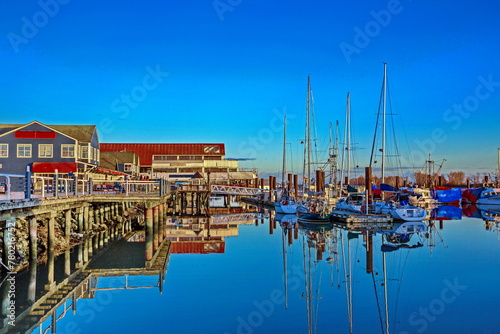 Promenade in the village of Steveston, summer grounds of restaurants and fishermen marina  at waterfront of Richmond City on a background of blue sky