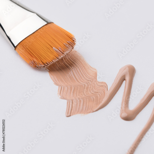 Make up brush and beige tone cream isolated view
