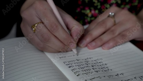 Person practices writing Arabic letters in a notepad, highlighting the concept of learning and mastering letters in a different language. Static Shot photo
