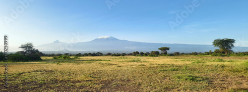 Beautiful panorama view African landscape with mountains and savannah. Kilimanjaro mountain Tanzania snow capped under cloudy blue skies captured whist on safari in Africa Kenya.