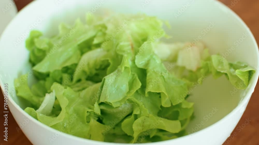 Food A white bowl with leaf vegetable lettuce leaves on a wooden table Food A white bowl with leaf vegetable lettuce leaves on a wooden table