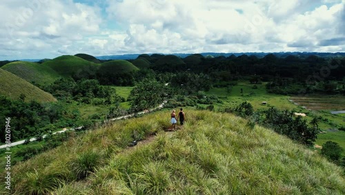 Aerial view of a couple walking in Chocolate Hills, Philippines. Traveling in Bohol island, enjoying tourist attractions. 