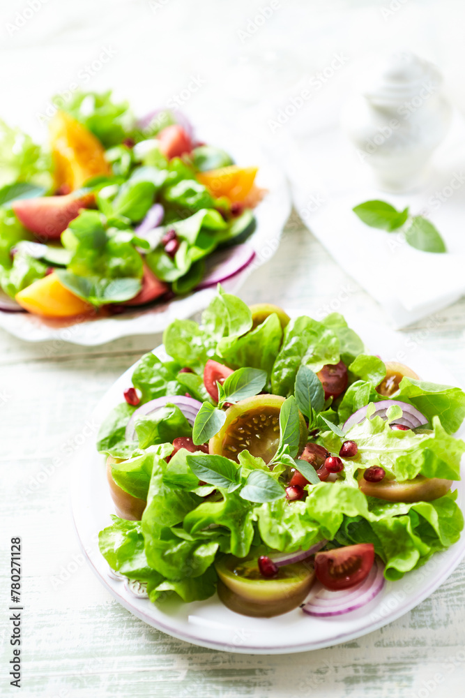 Salad with red and yellow Tomatoes and Pomegranate Seeds on bright wooden Background. Close up. Salad with red and yellow Tomatoes and Pomegranate Seeds on bright wooden Background. Close up.
