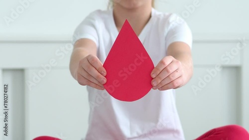 Anemia and World Blood Donor Day concept. Children's hands hold a symbol from a drop of blood on a white background. Blood transfusion. Helping the sick. Request for help. Medicine concept