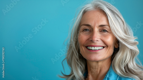 Frau Mitte 50 lächelnd vor blauen Hintergrund, KI generiert photo