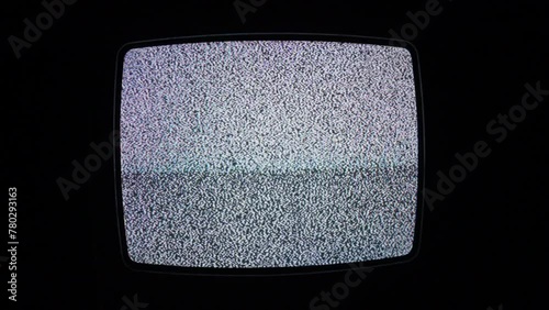 A full screen shot of an old cathode television set showing only white noise iin a dark and isolated room. photo