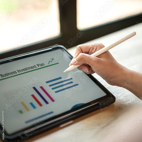 A person is using digital pen to working on tablet screen to review and analyst the 2024 business investment plan and project data. Business and finacial working with techologyo. Selective focus. photo