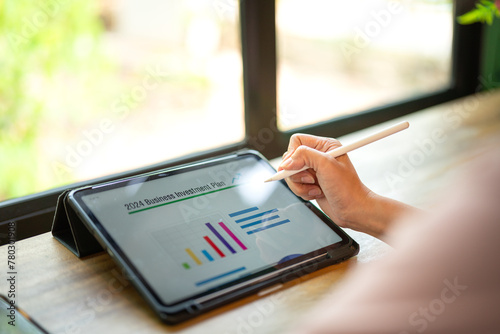 A person is using digital pen to working on tablet screen to review and analyst the 2024 business investment plan and project data. Business and finacial working with techologyo. Selective focus.