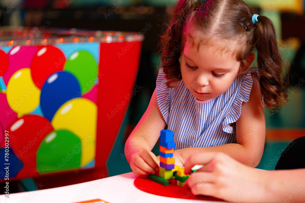 Curly-Haired Toddler Girl Concentrating on Building With Colorful Blocks Indoors Curly-Haired Toddler Girl Concentrating on Building With Colorful Blocks Indoors