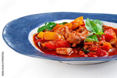 Roast chicken stew with vegetables and tomatoes served in a plate on a white background. Chakhokhbili made from chicken pieces, Georgian cuisine, close up