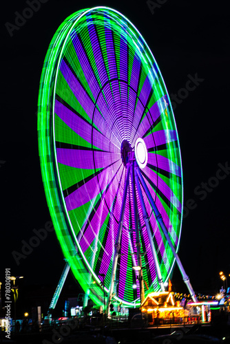 Carnival lights at night - The fun of summertime carnival and fair rides at night with colorful lights on thrill rides and attractions