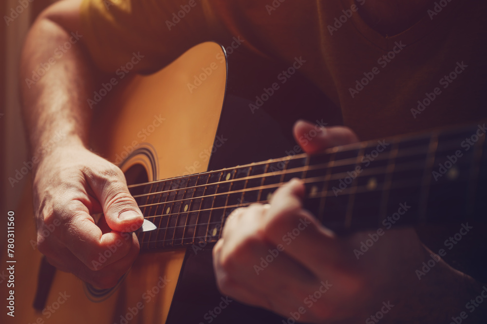 Fototapeta premium Man playing acoustic guitar at home, low key image