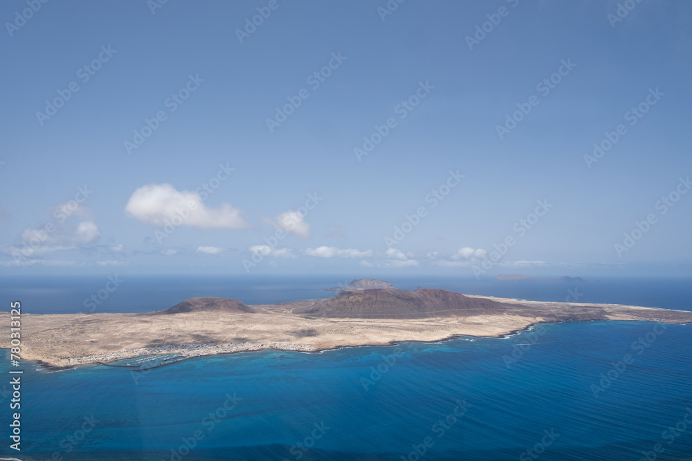 Views of the island of La Graciosa from the viewpoint of El Rio. Turquoise ocean. Blue sky with big white clouds. Caleta de Sebo. Town. volcanoes. Lanzarote, Canary Islands, Spain