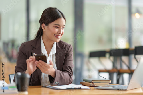 Asian businesswoman Company sales manager while talking on the phone with a customer, looking at documents, files, financial details, agreements, and business contracts on a laptop in the office.