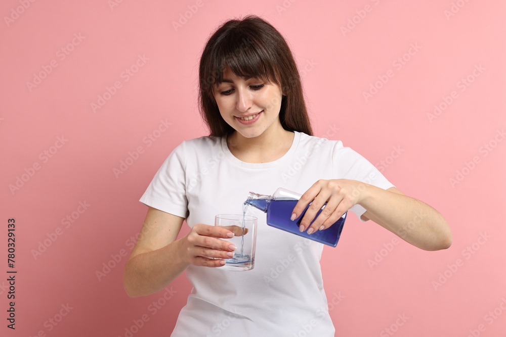Young woman using mouthwash on pink background Young woman using mouthwash on pink background