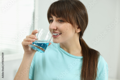 Young woman using mouthwash in bathroom. Oral hygiene