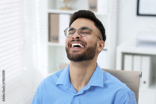 Portrait of handsome young man laughing in office