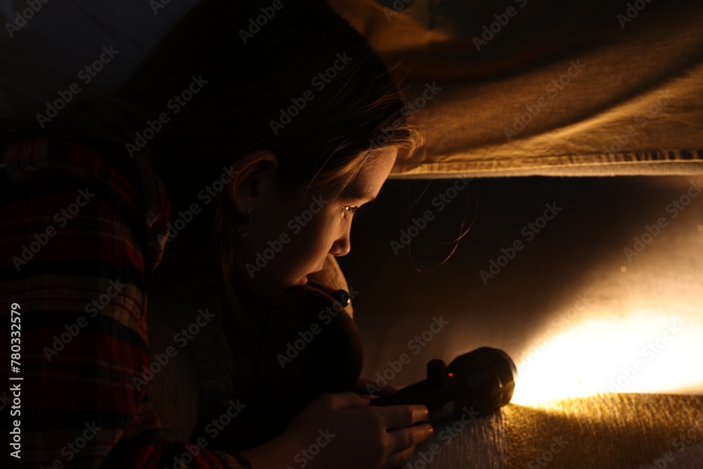 Fototapeta premium Little girl with flashlight looking for monster under bed at night