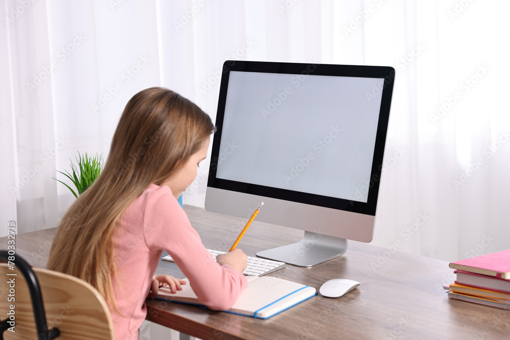 E-learning. Cute girl taking notes during online lesson at table indoors E-learning. Cute girl taking notes during online lesson at table indoors