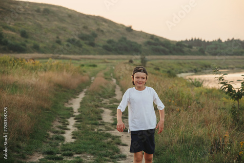 Happy boy having fun on grass field wearing white t-shirt photo