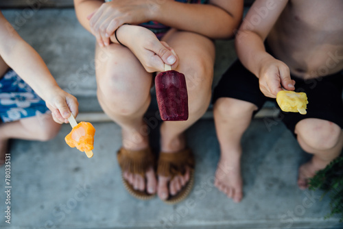 Overhead view of three kids with popsicles sitting outside photo