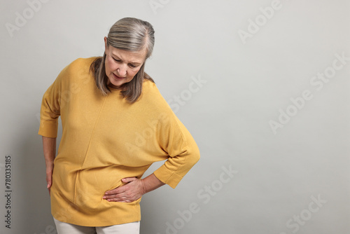 Arthritis symptoms. Woman suffering from hip joint pain on gray background, space for text photo