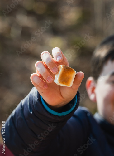 Close up of child's hand holding brown toasted marshmallow.