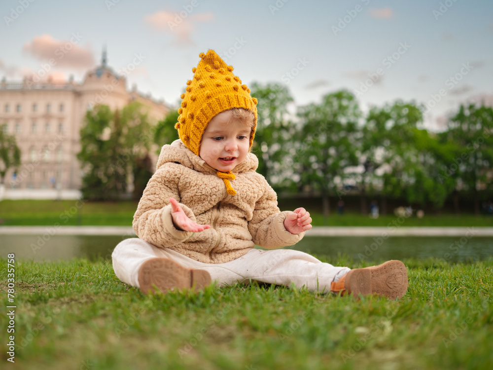 A 3-year-old girl is sitting on the grass in the central park. A 3-year-old girl is sitting on the grass in the central park.