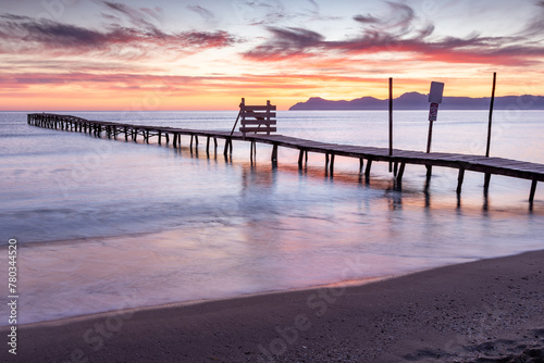 Beautiful sunrise on a beach with old wooden jetty in Platja de Muro, Majorca, Balearic Islands, Spain photo