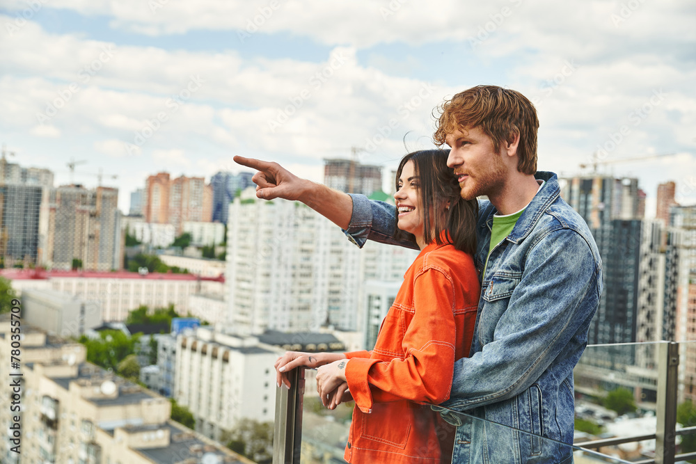 A man and a woman standing confidently on the rooftop of a building, looking out at the city skyline with awe and determination - obrazy, fototapety, plakaty 