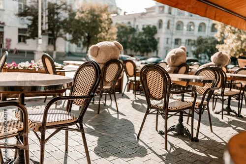 A restaurant with a lot of chairs and tables. There are two teddy bears on the tables. © svetograph