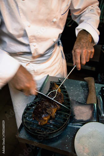 A skilled chef is carefully carving expertly roasted meat on a cutting board in a professional kitchen setting photo