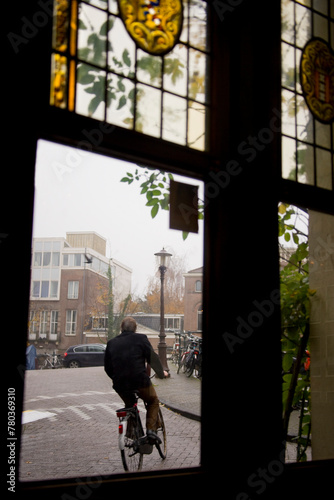 View of a cyclist through a vintage glass window with reflections of a building's exterior photo