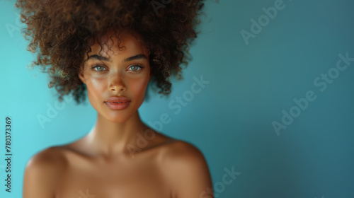 Attractive young naked african american woman with lush curly hair posing confidently in a photo studio with a serene expression.