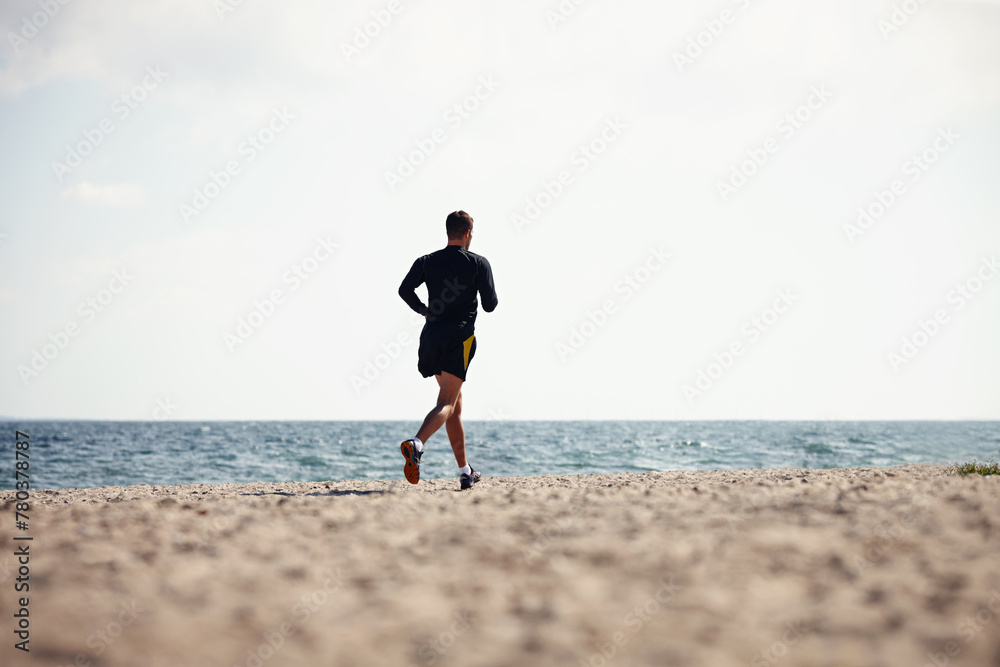 Sports, man and jogging in outdoor for fitness, health and wellness on beach for workout or exercise. Male athlete, training and cardio with endurance, muscles and strength for healthy living or gym